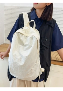 Detail showing the textured white nylon fabric and side view of the minimalist backpack