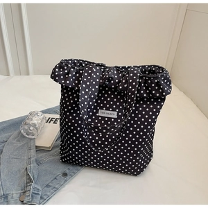 Polka dot canvas tote bag with ruffled edges and double top handles on white bed