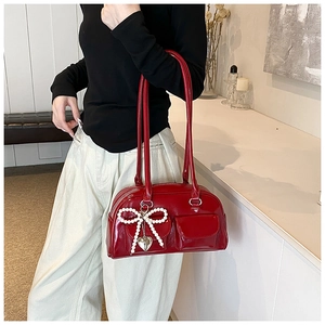 Detail of red patent leather handbag with pearl bow charm and silver heart pendant