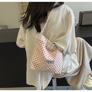 Detail of canvas crossbody bag with red polka dots, lace ruffles, and pearl accents