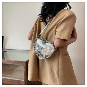 Detailed view of silver sequin heart cross body bag on model with slim shoulder strap