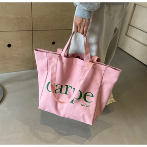 Detailed view of pink canvas tote bag with green carpe lettering and sturdy handles