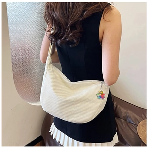 Detail view of off-white corduroy hobo bag featuring a colorful cartoon bear pendant