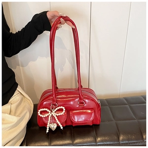 Detail of red glossy PU leather shoulder bag with pearl bow charm and heart pendant
