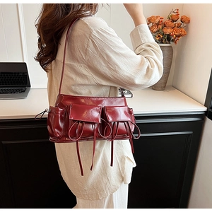 Detail of burgundy PU leather shoulder bag with vintage pockets and glossy texture