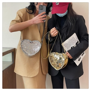 Close-up of heart-shaped sequin crossbody bags in gold and silver for women