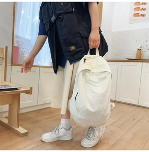 Detailed view of minimalist white nylon backpack with black zipper in lifestyle setting