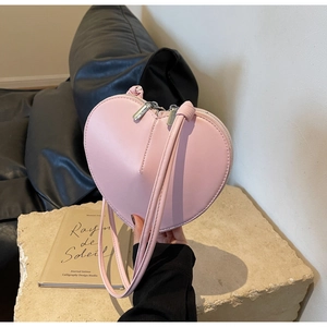 Dettaglio della borsa a tracolla rosa a forma di cuore con cerniere su piedistallo di pietra