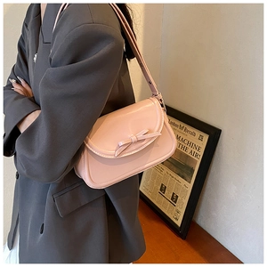 Dettaglio della borsa a tracolla rosa in ecopelle con fiocco decorativo su una modella