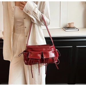 Detail of burgundy PU leather shoulder bag with industrial cargo pockets and drawstrings