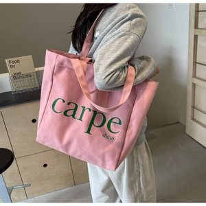 Detail of a large pink canvas tote bag with green carpe dienn print on a shoulder strap