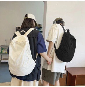 Lifestylescene showing two large minimalist nylon backpacks in cream and black colors