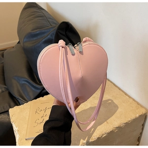 Dettaglio di una borsa a spalla rosa a forma di cuore con texture liscia e zip in metallo