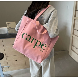 Detail view of pink canvas tote bag with carpe dienn print on a model's shoulder