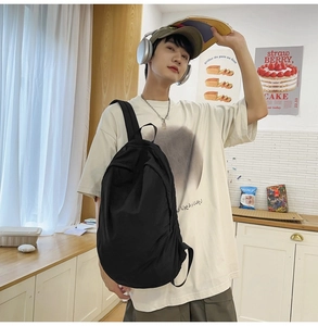 Detailed view of spacious black nylon backpack worn by a model in a casual home setting