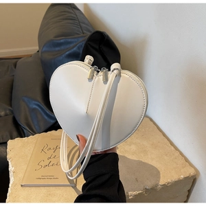 Dettaglio della borsa a tracolla bianca a forma di cuore con doppie cinghie e zip annodate