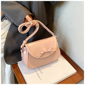 Borsa a tracolla rosa in pelle PU con fiocco decorativo su un tavolo in legno