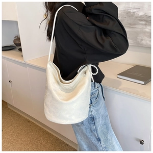 Close-up of a white textured PU bucket bag featuring a decorative pearl knot charm