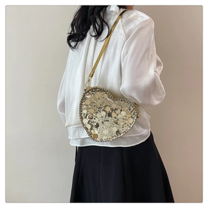 Detail of a heart-shaped crossbody bag with golden sequins and matching thin strap