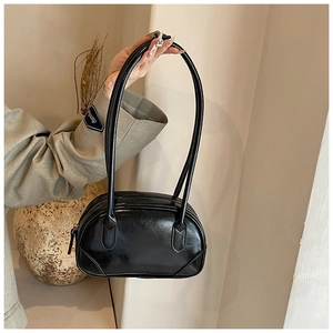 Detail of glossy black PU leather handbag with sleek handles and reflective finish
