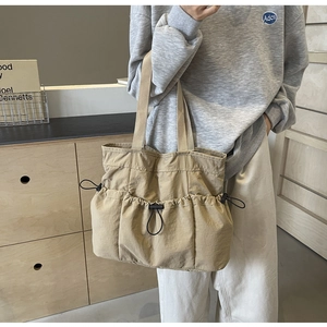 Detail der khakifarbenen Canvas-Tragetasche mit mehreren Kordelzugtaschen für Stauraum
