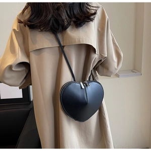 Dettaglio di una borsa a tracolla nera opaca a forma di cuore con cerniere argentate