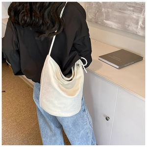 Detailed view of a white PU leather shoulder bag with elegant pearl charm on a model