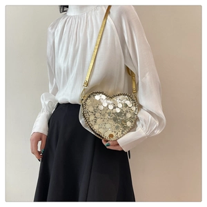 Detail shot of heart-shaped crossbody bag featuring sparkling gold and silver sequins