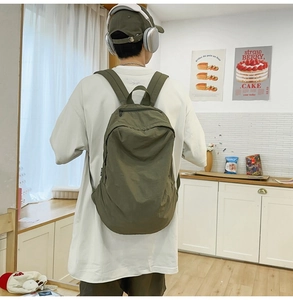 Detail view of army green nylon backpack with wide straps worn by a male model