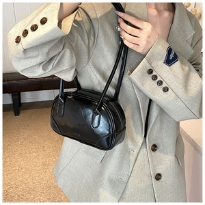 Classic black glossy PU leather underarm bag with zipper closure shown on a model