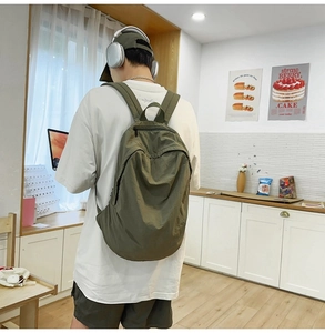 Rear view of model wearing a minimalist olive green nylon backpack with top handle and straps