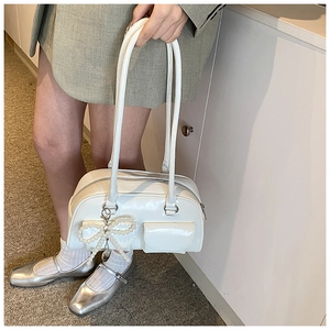 Close-up of a white PU leather shoulder bag featuring a pearl bow charm and flap pocket