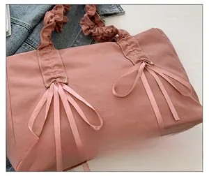 Vue détaillée du sac cabas en toile rose avec bandoulière plissée et nœuds en ruban
