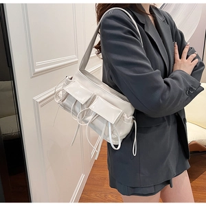Detail of a chic off-white PU leather shoulder bag with decorative drawstring accents