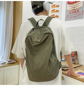 Olive green nylon backpack worn by model, showing adjustable straps and soft texture