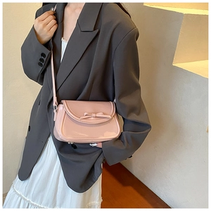 Borsa a tracolla rosa in ecopelle con fiocco indossata da una modella in ambiente minimal