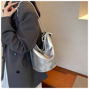 Detail of silver metallic hobo bag featuring pearl beads and charms on a grey blazer