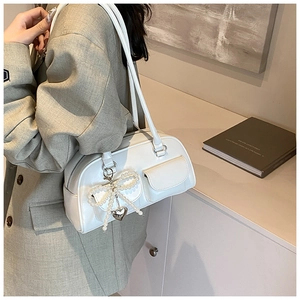Detail of white PU baguette bag with pearl bow charm and metal heart pendant