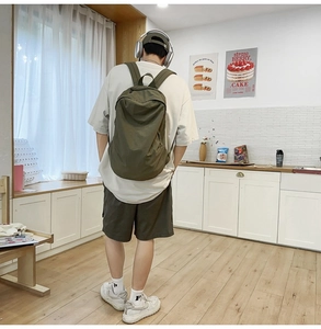 Model wearing a minimalist army green nylon backpack for casual commuting and urban style