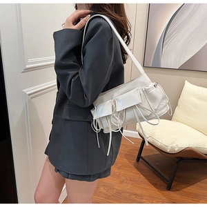 Detail view of white PU leather shoulder bag featuring multi-pocket design and pleated cords