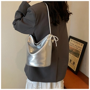 Detail of silver metallic PU bucket bag with pearl bow and heart charm pendant