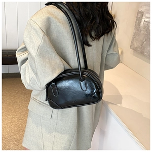 Detail of the glossy black PU leather shoulder bag worn with a grey oversized blazer