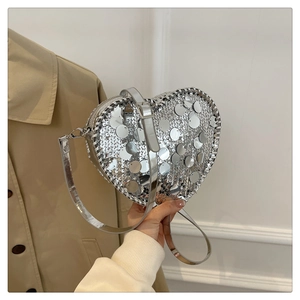 Silver sequin heart-shaped crossbody bag with adjustable strap and shiny metallic finish