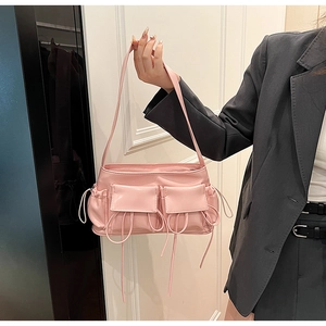 Detail of pink faux leather shoulder bag with glossy finish and decorative bow straps