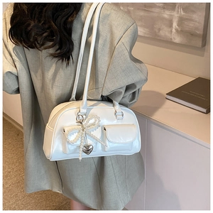 Close-up of white PU leather bowling bag featuring pearl bow and silver heart pendant