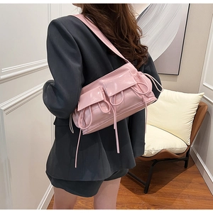 Detail of pink glossy PU leather shoulder bag with pockets and drawstrings on gray suit