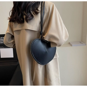 Dettaglio di una borsa a tracolla nera a forma di cuore con tracolla a nodo e zip