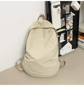 Minimalist beige nylon backpack featuring waterproof fabric and top handle for commute