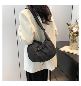 Detail view of black nylon crossbody bag featuring adjustable straps and drawstring closure