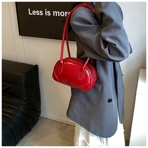 Close-up of red glossy patent leather underarm bag featuring a sleek pillow shape